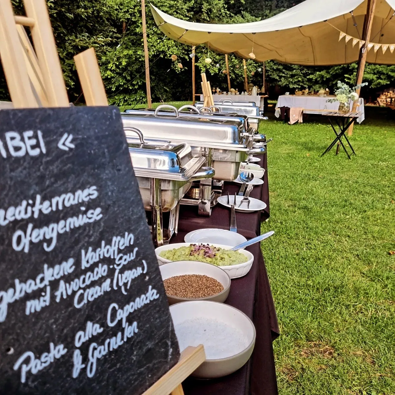 Cateringbuffet unter einem Festzelt im Grünen