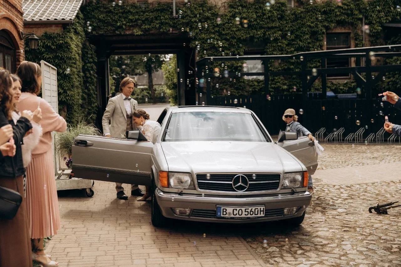 Brautpaar bei der Ankunft im historischen Mercedes vor seinen Gästen