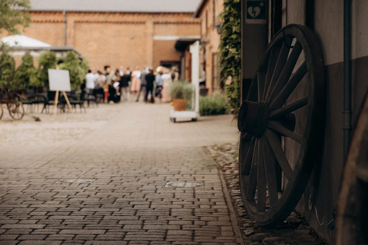 Historisches Wagenrad und Hochzeitsgäste im Innenhof