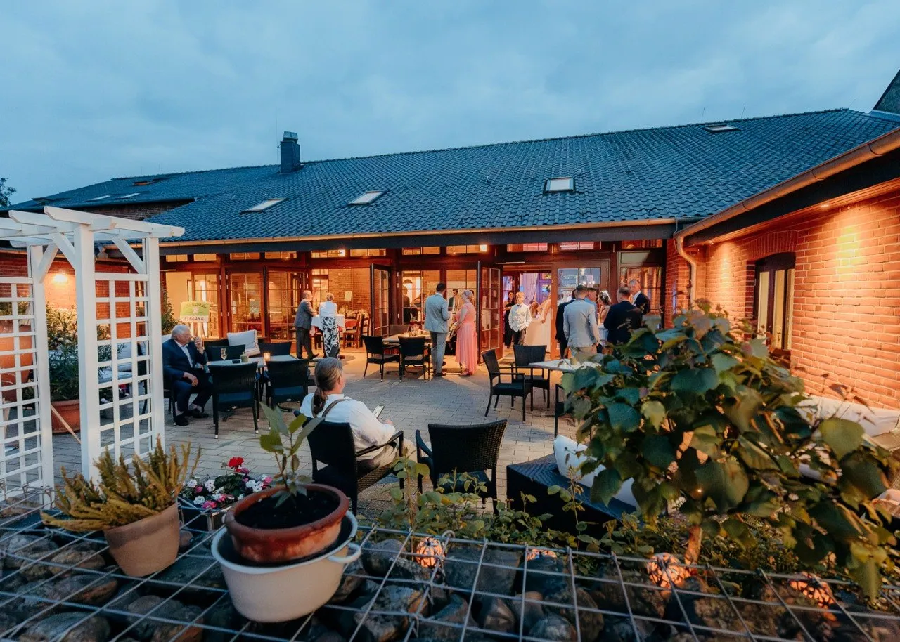 Hochzeitsgäste beim abendlichen Empfang im beleuchteten Innenhof