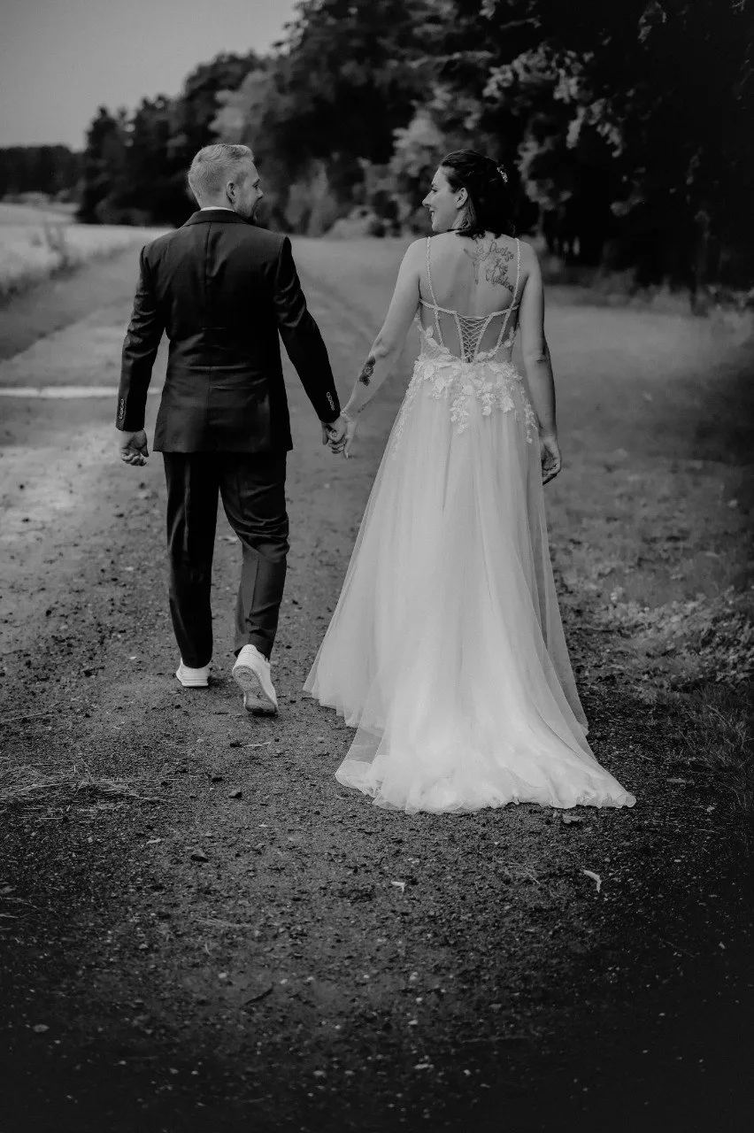 Brautpaar Hand in Hand auf einem Feldweg
