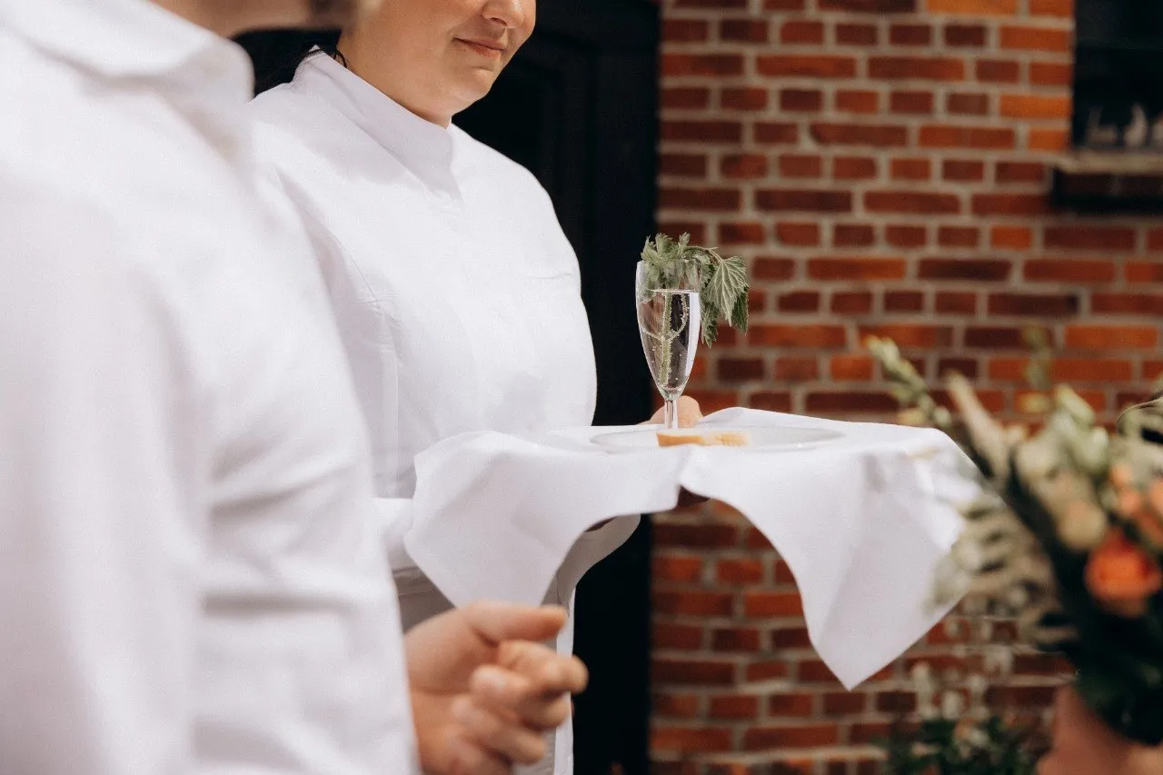 Service mit Sektglas vor einer Backsteinwand