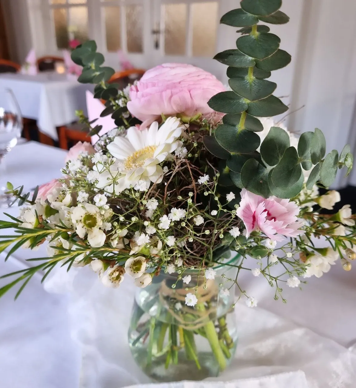 Rosa-weißer Blumenstrauß mit Eukalyptus auf einem gedeckten Tisch